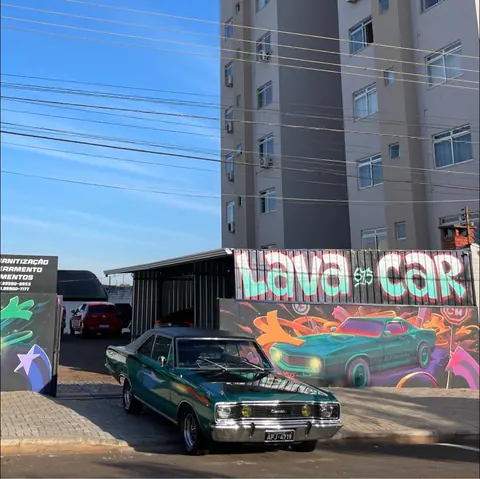 Carro clássico verde em frente ao mural do lava car